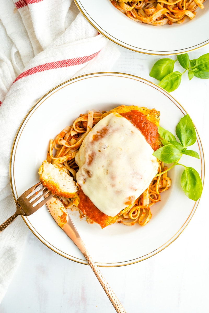 An overhead picture of a dish of gluten free chicken parmesan with a piece cut off.