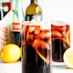 A red wine cocktail garnished with lemon in a highball glass