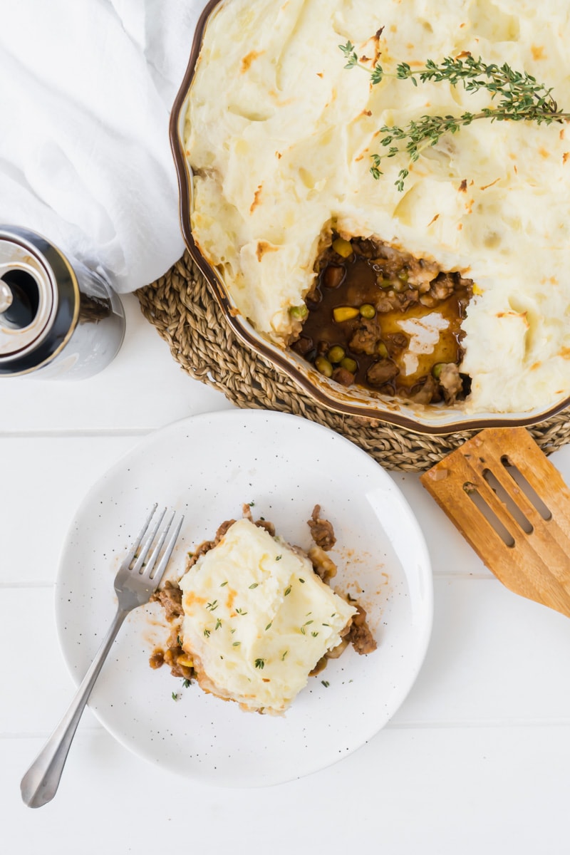 An overhead picture of an easy cottage pie with a slice on a plate nearby