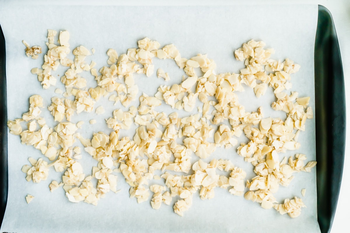A baking sheet of honey coated almonds slices.