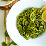 A white bowl filled with a recipe for fiddleheads