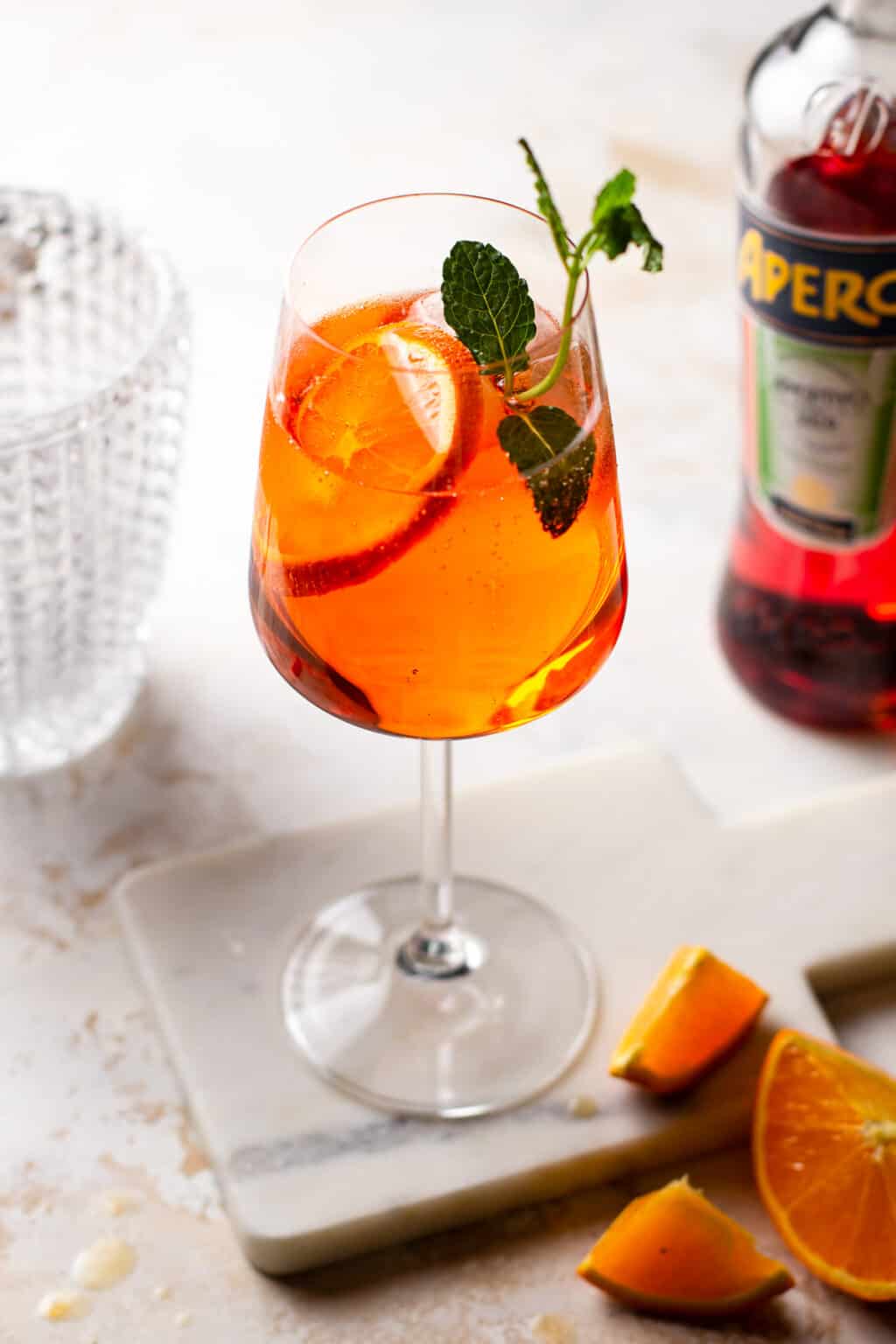 An Aperol Spritz in a wine glass decorated with fruit.