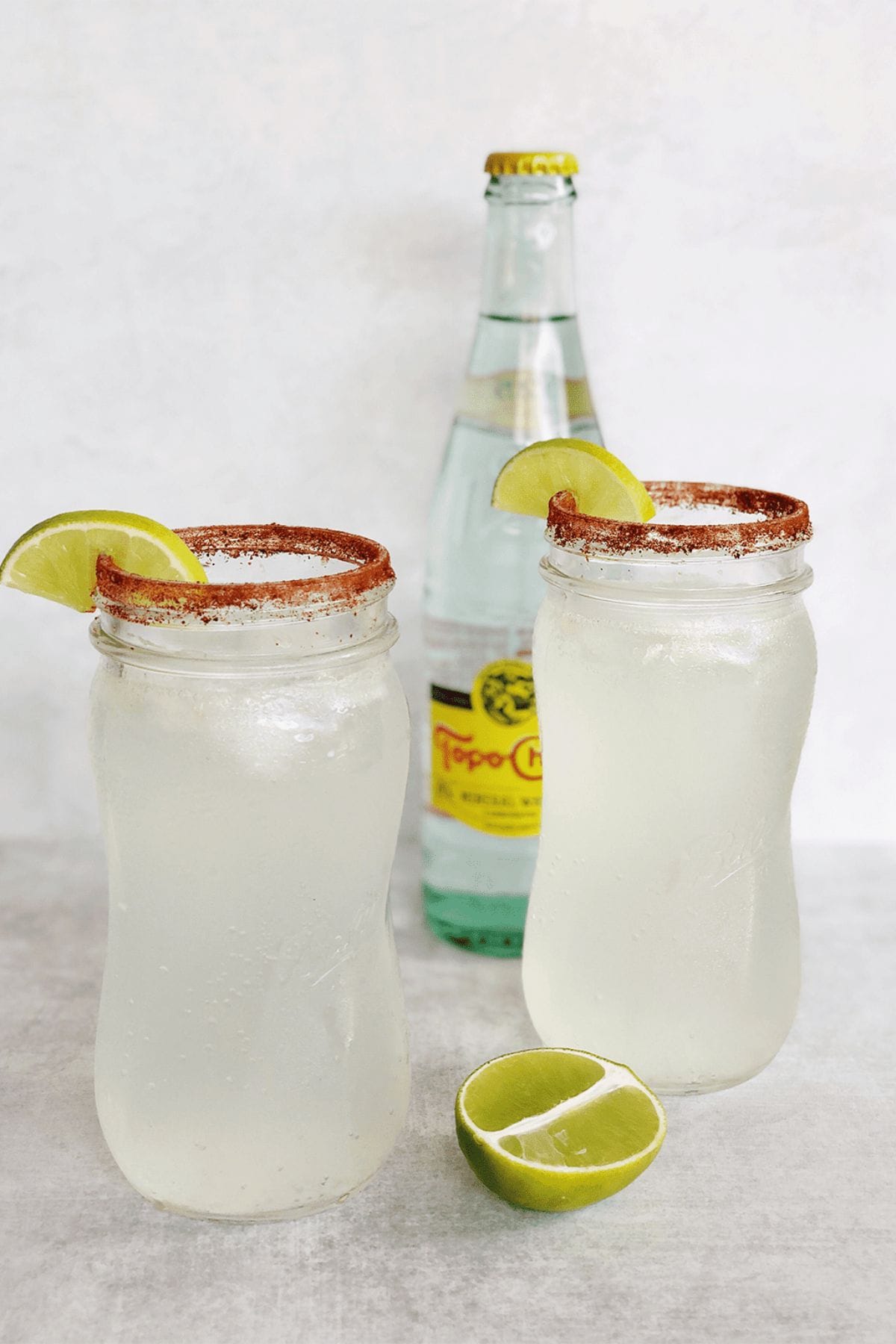 Two cocktail glasses rimmed with chili powder and lime.