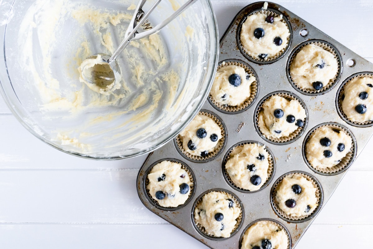 A muffin tin filled with blueberry muffin batter.