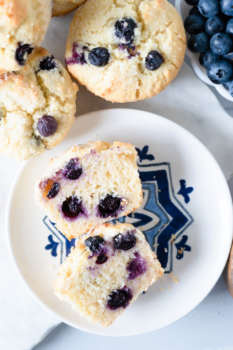 A blueberry muffin cut in half on a plate.