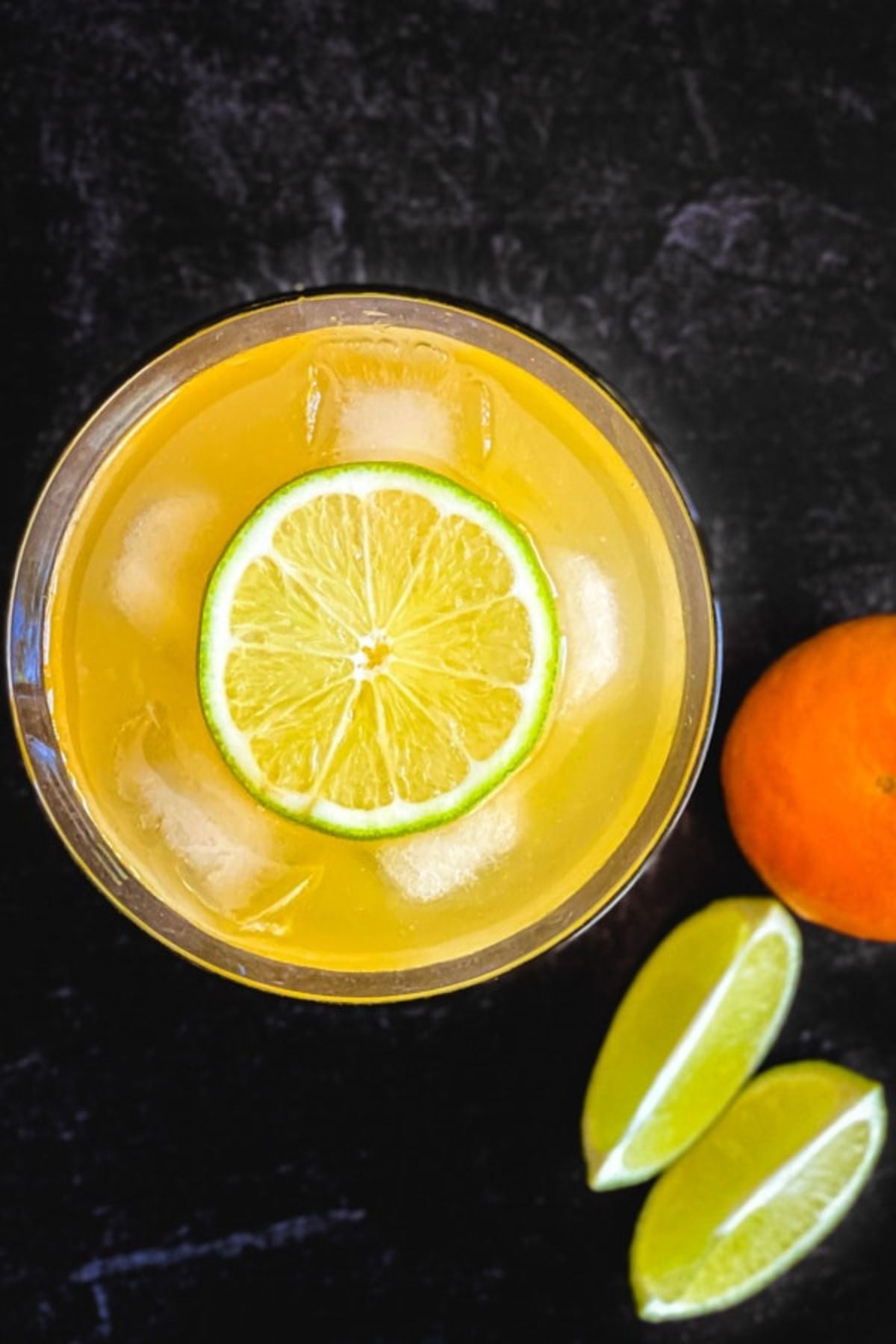 An orange drink shot from above with an wheel of lime in the centre.