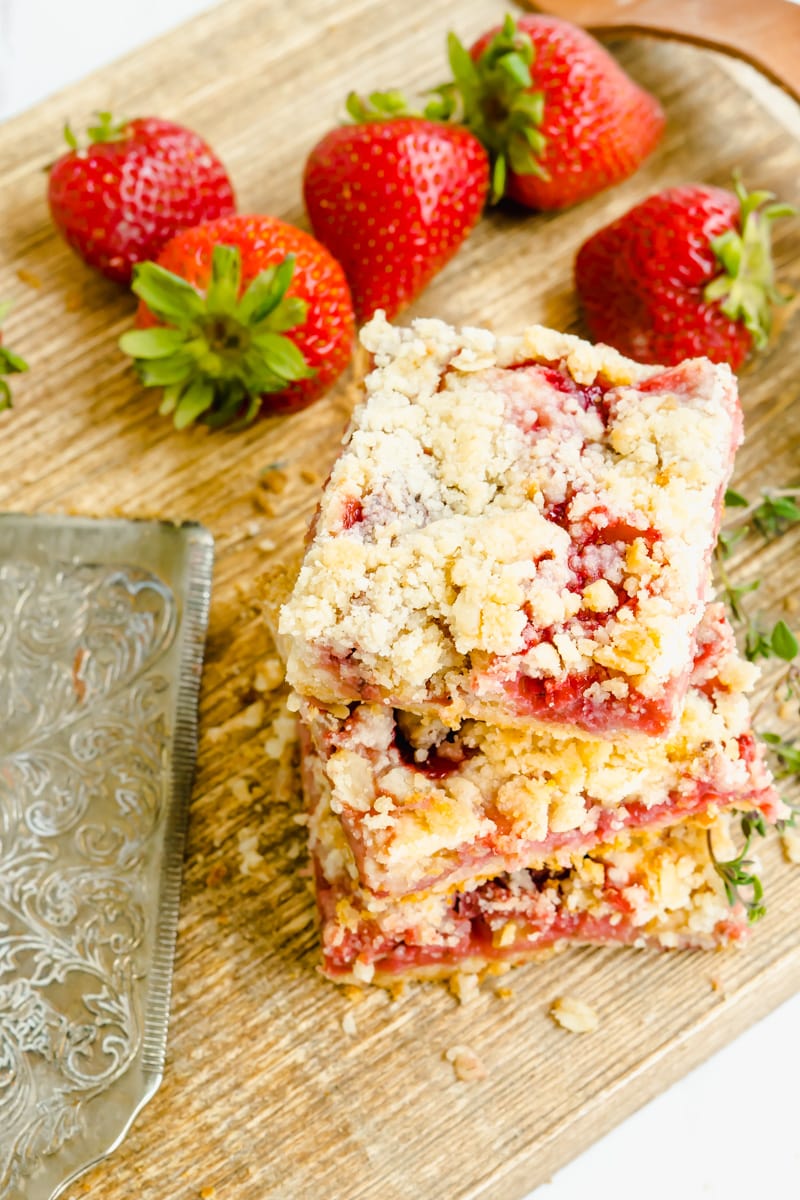 Overhead shot of strawberry crumble dessert bars on a cutting board.
