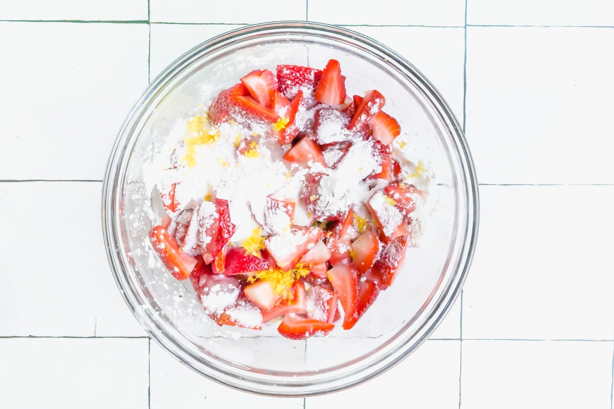 A bowl of cut strawberries with sugar and flour for a filling.