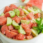 A cucumber and watermelon salad in a white bowl.