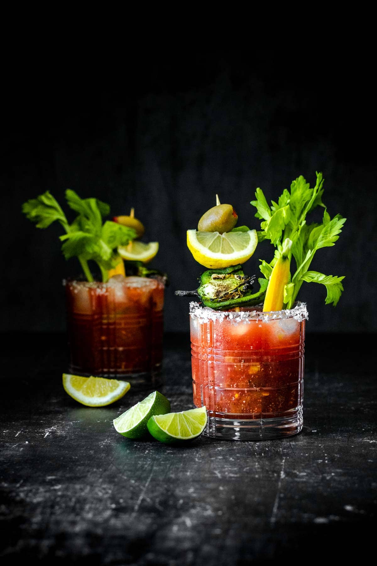 A skinny bloody mary recipe decorated with a celery stalk and olives.