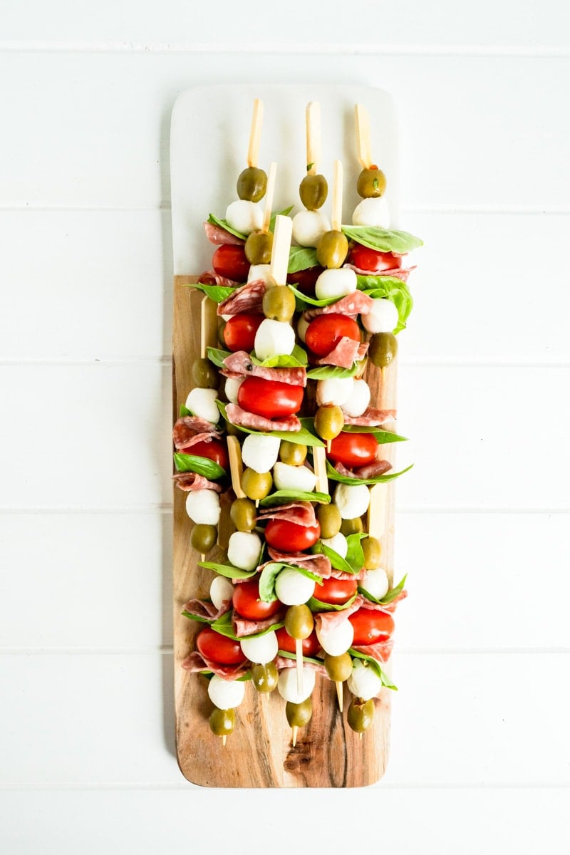 A platter of antipasto skewers on a white table.