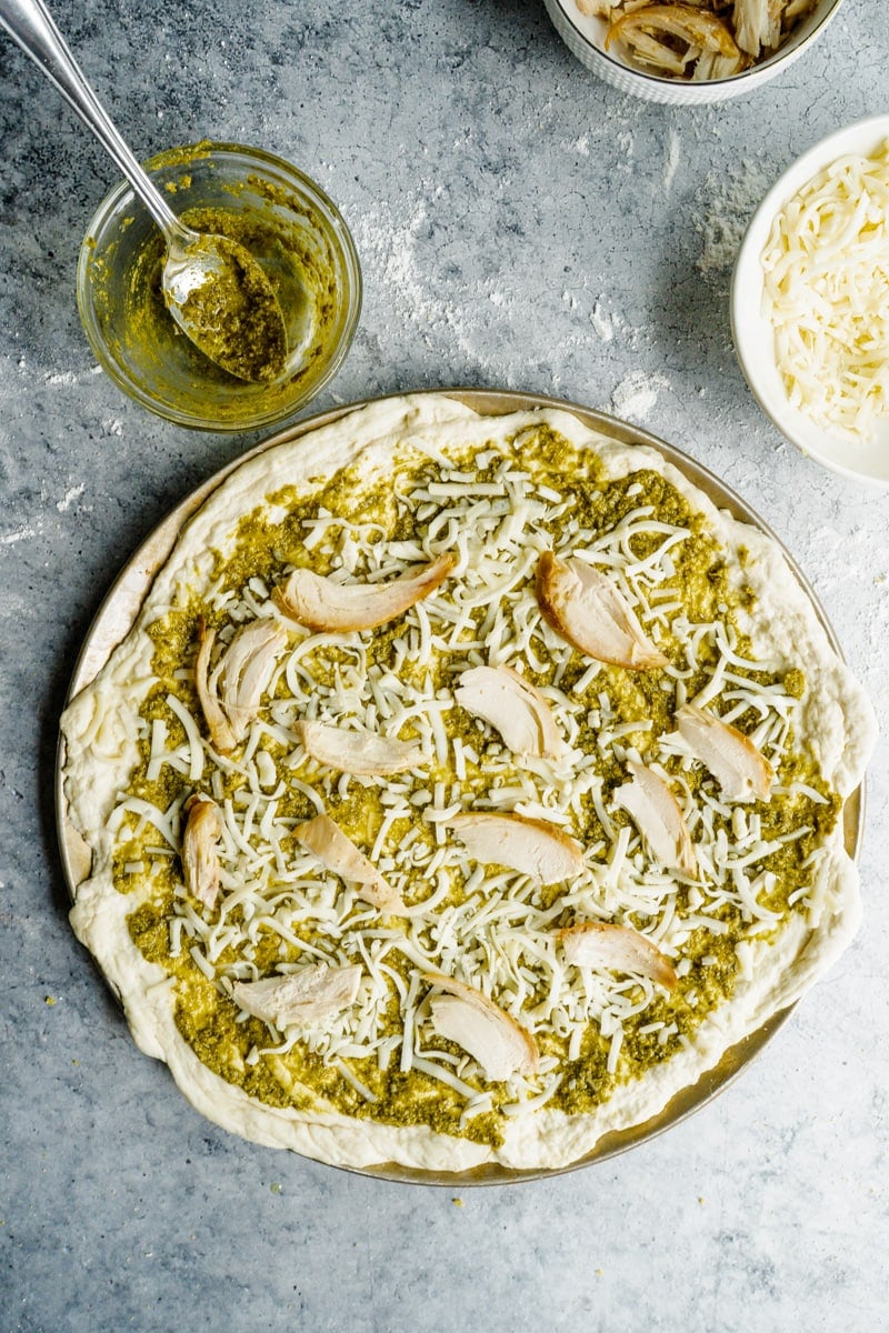 A chicken pizza recipe unbaked on a pan.