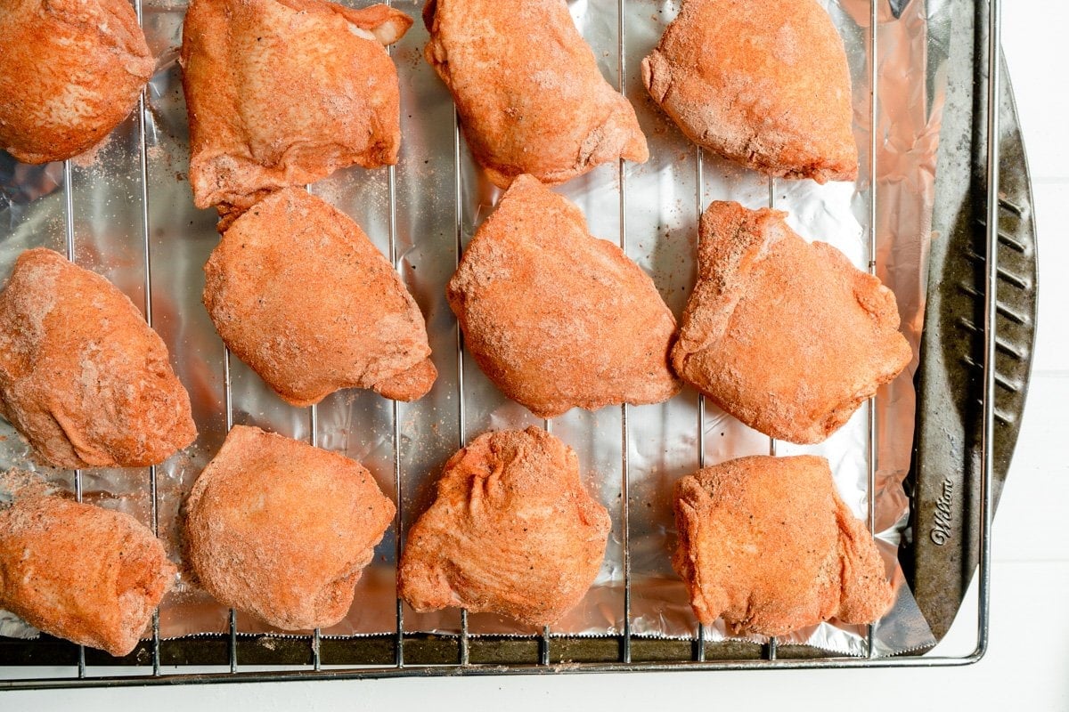 seasoned chicken thigh pieces laid out on a cooking rack