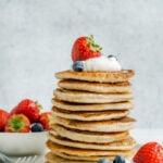 Cottage cheese pancakes stacked tall with fruit.