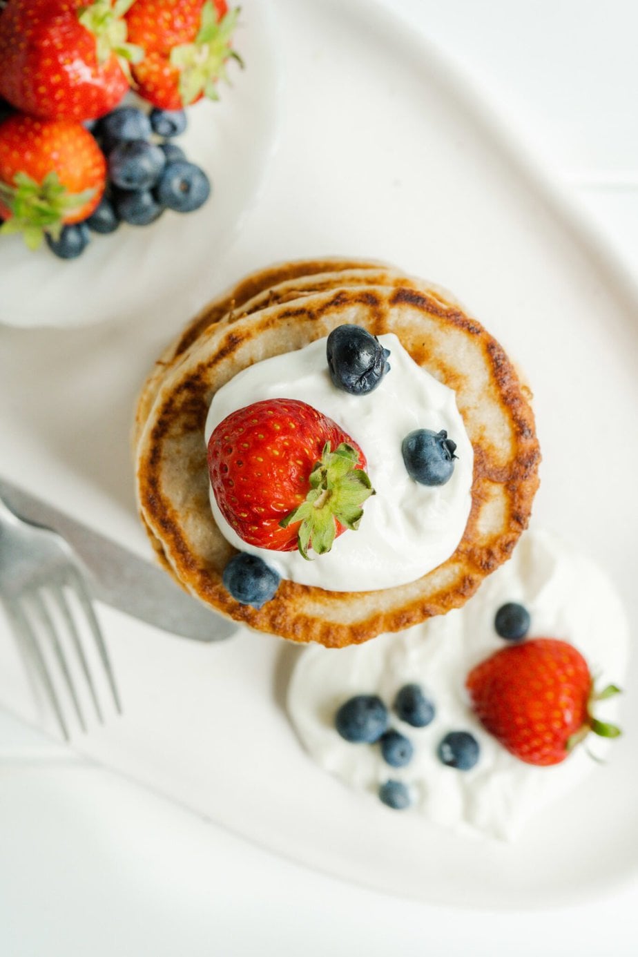 overhead view of a stack of pancakes with fruit on top
