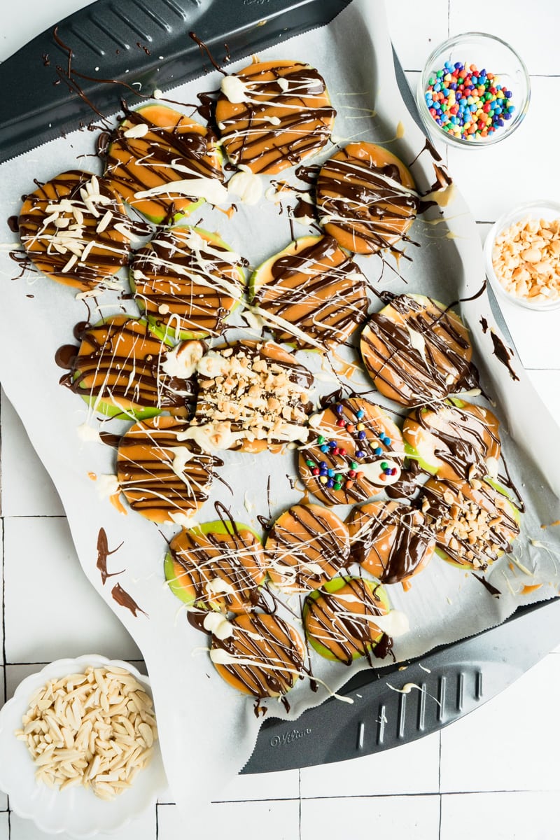 Caramel Apple Slices Recipe on a baking sheet decorated with candy.