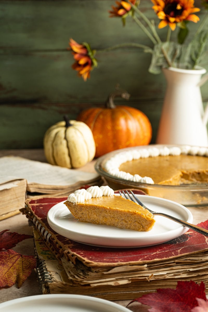 A slice of keto pumpkin pie on a fall table.