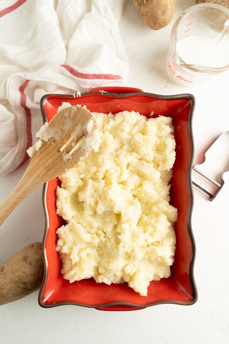 Easy homemade mashed potatoes in a red dish on a table.