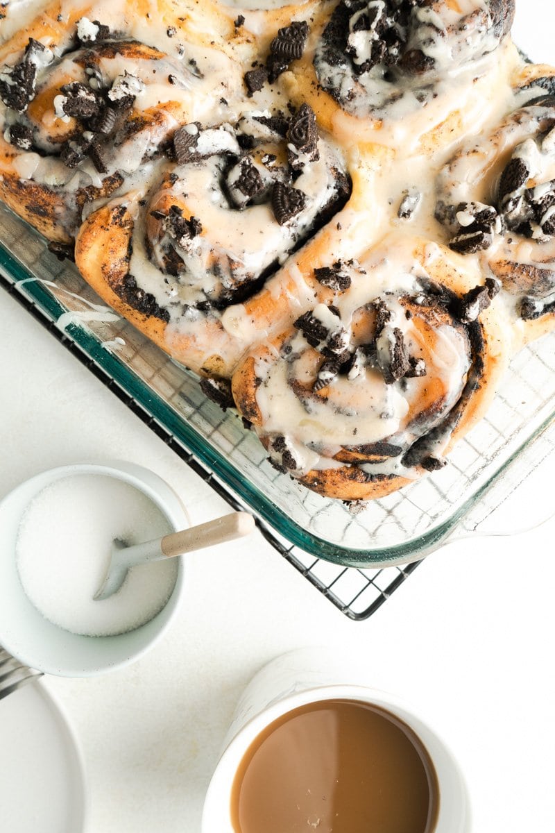 A table showing a cookies and cream cinnamon roll on a plate with more nearby