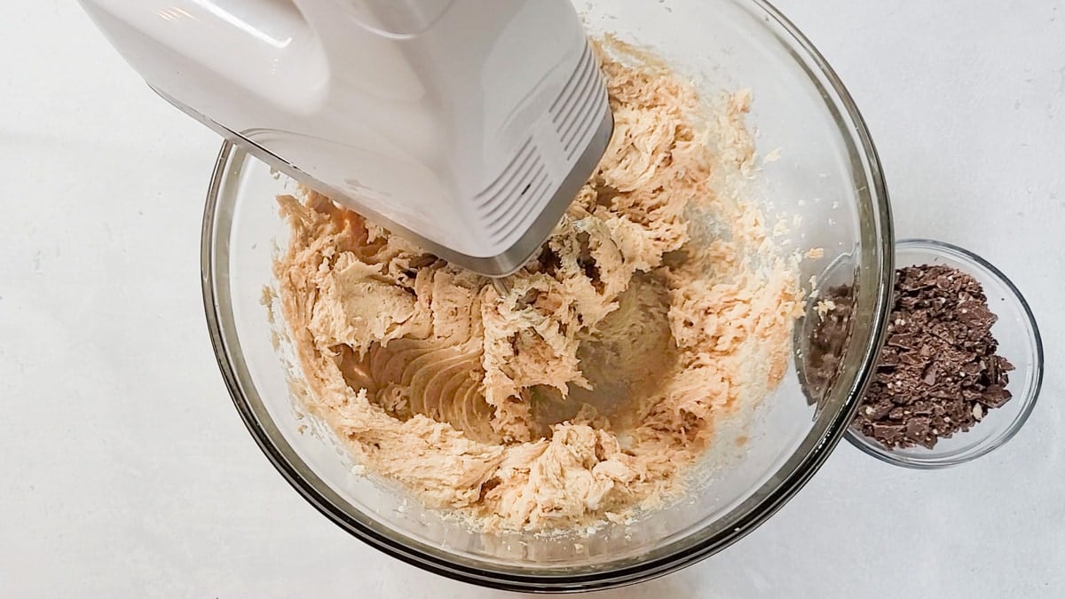 Peanut butter cheesecake filling being whipped with a hand mixer.