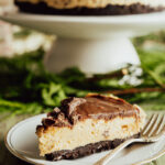 A slice of Philadelphia no-bake cheesecake on a plate with winter greens in the background.