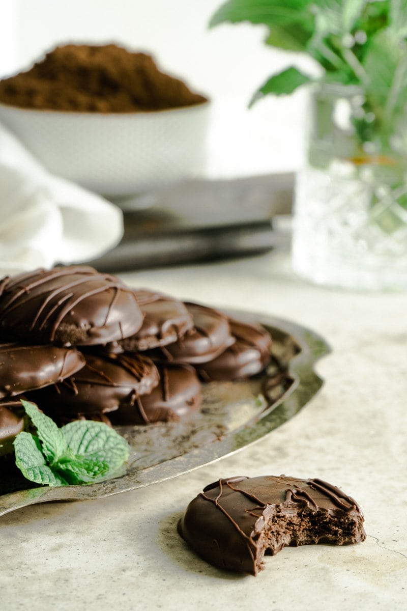 A tray of thin mint cookies and one with a bite taken.