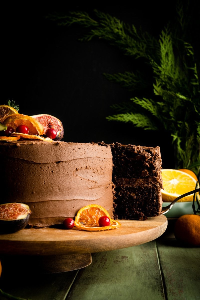 A chocolate cake made with orange having a slice taken.