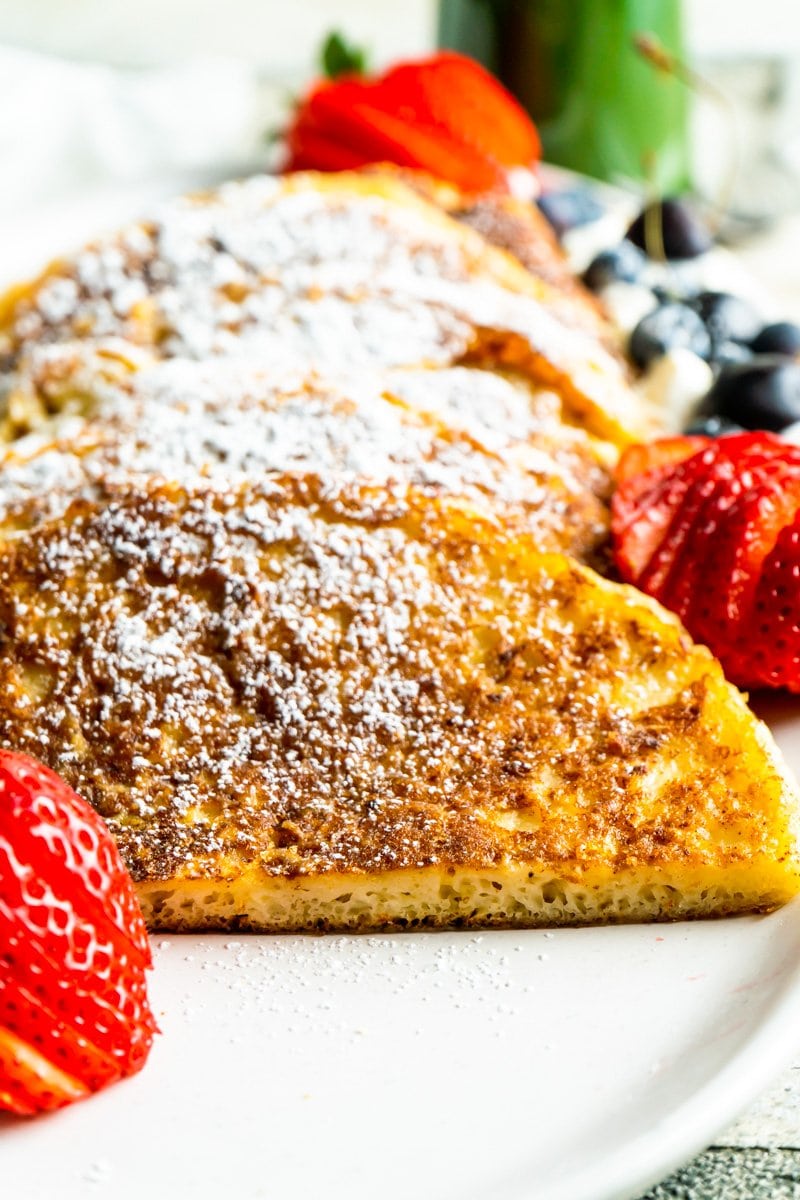 Cinnamon french toast pancakes on a platter with berries and powdered sugar.