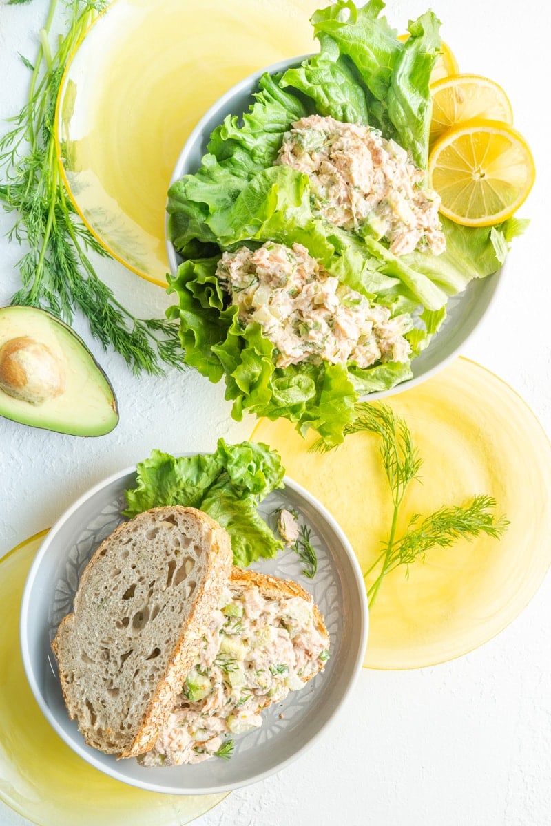 Salmon and avocado salad made with bread and lettuce leaves served on yellow plates.