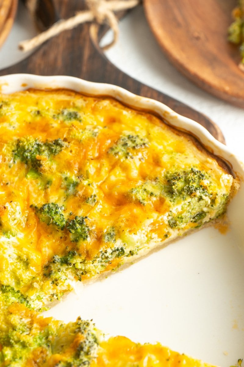 Close up of a vegetarian quiche made with broccoli and cheddar with a slice removed.