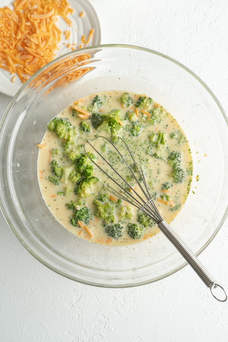 Ingredients for a simple breakfast quiche with broccoli in a bowl being whisked.