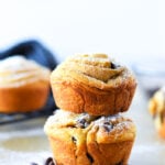 A recipe for cruffins with two stacked on a table with some chocolate chips.
