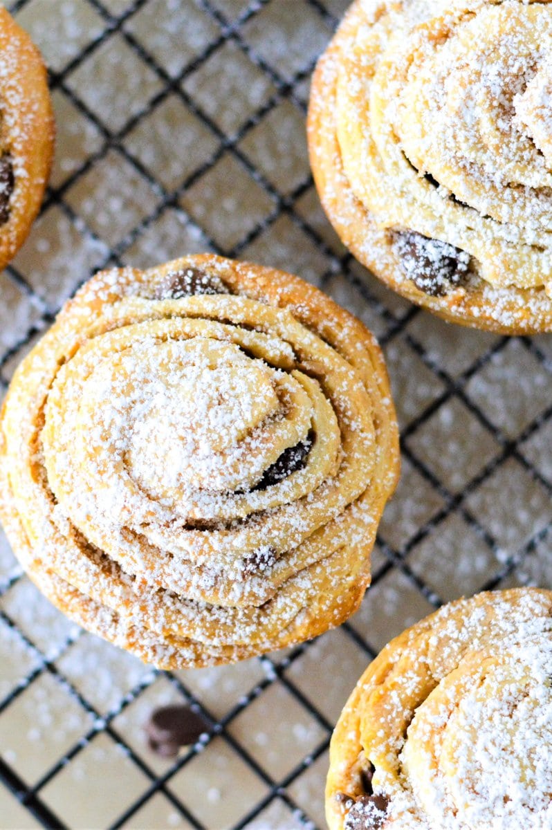 Cruffins on a cooling rack sprinkled with powdered sugar.