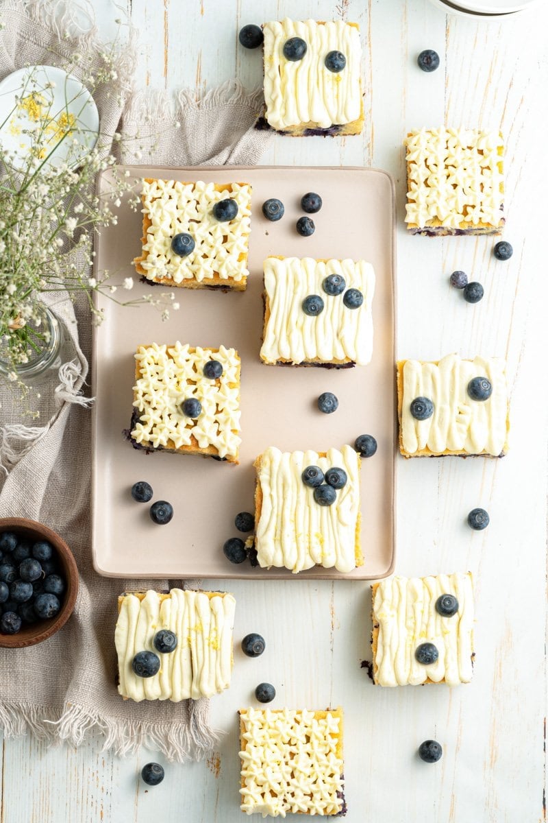 Slices of lemon blueberry tea cake on a table decorated with babies breath and blueberries.