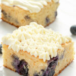A slice of lemon and blueberry cake decorated with cream cheese frosting.