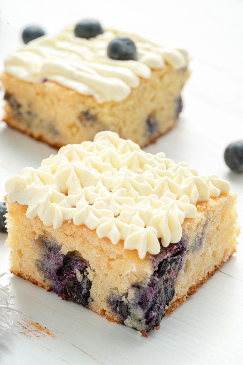 A slice of lemon and blueberry cake decorated with cream cheese frosting.