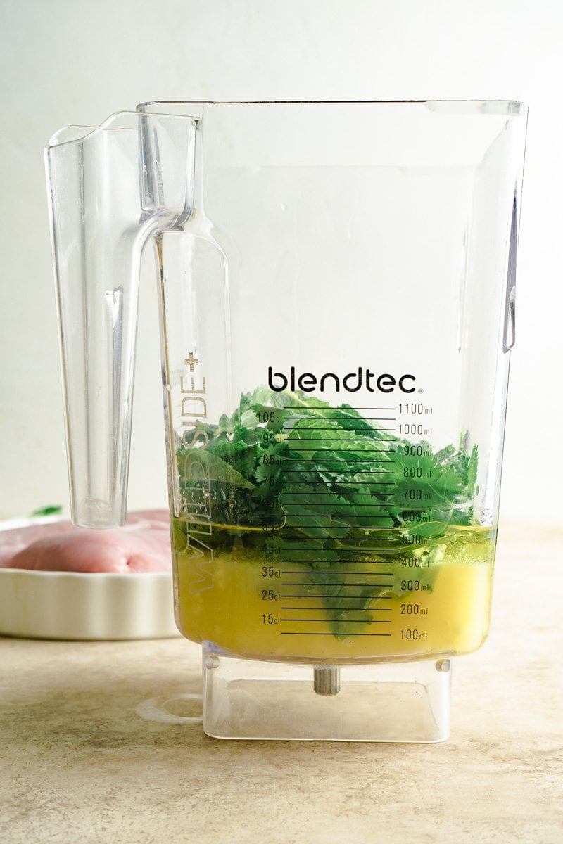 Orange juice and herbs in a blender for a mojo pork recipe