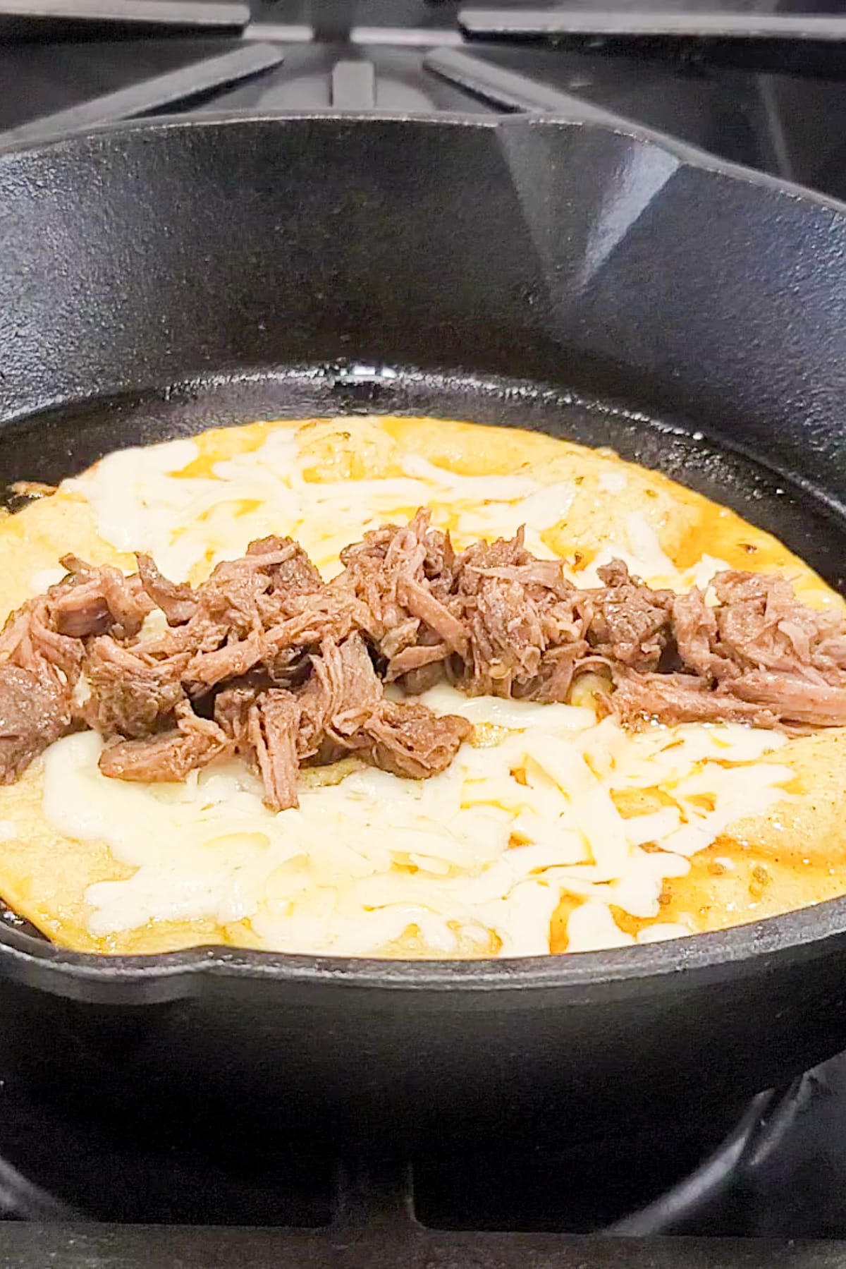 A Beef birria taco being heated in a skillet.
