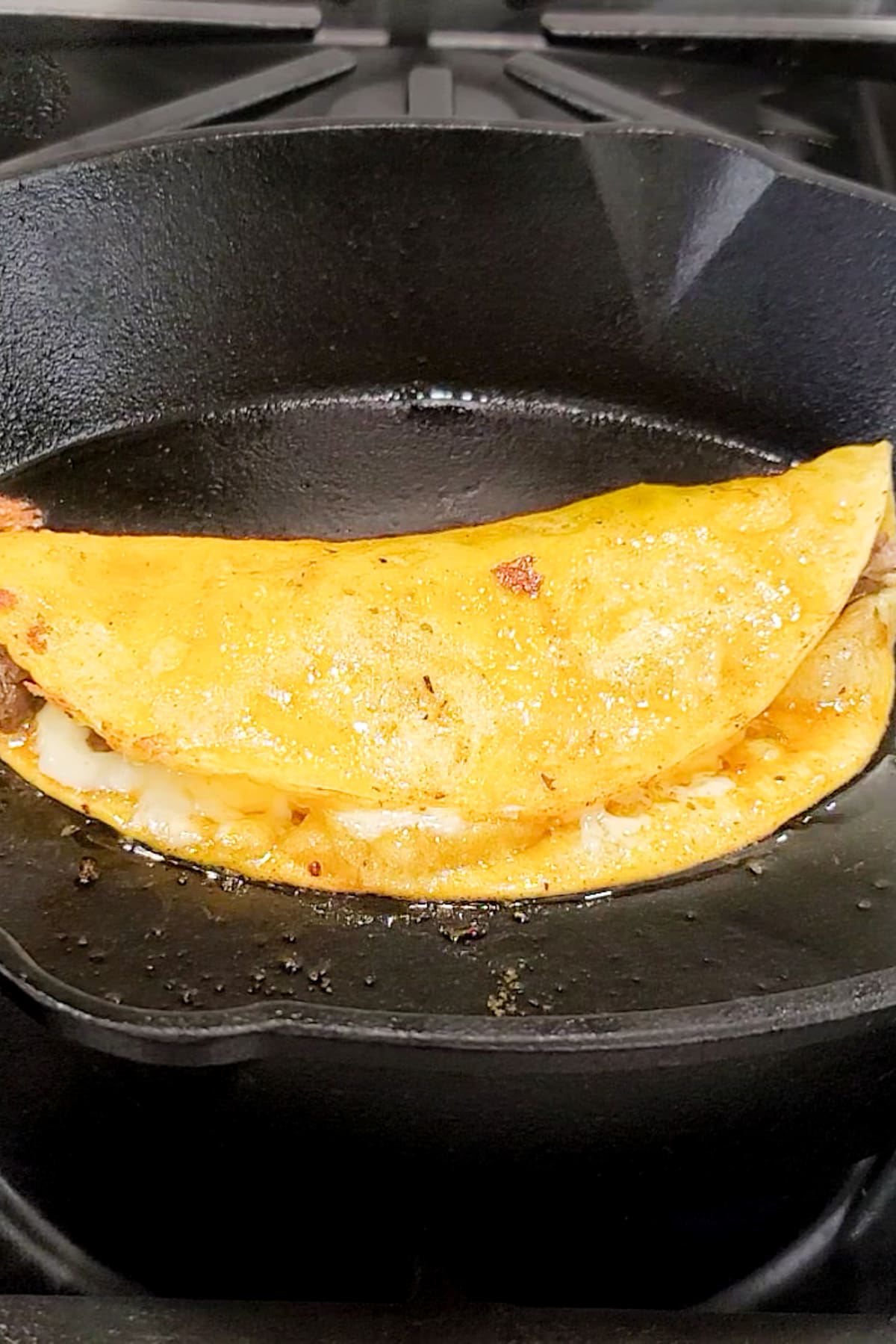 A queso birria taco being made in a skillet.