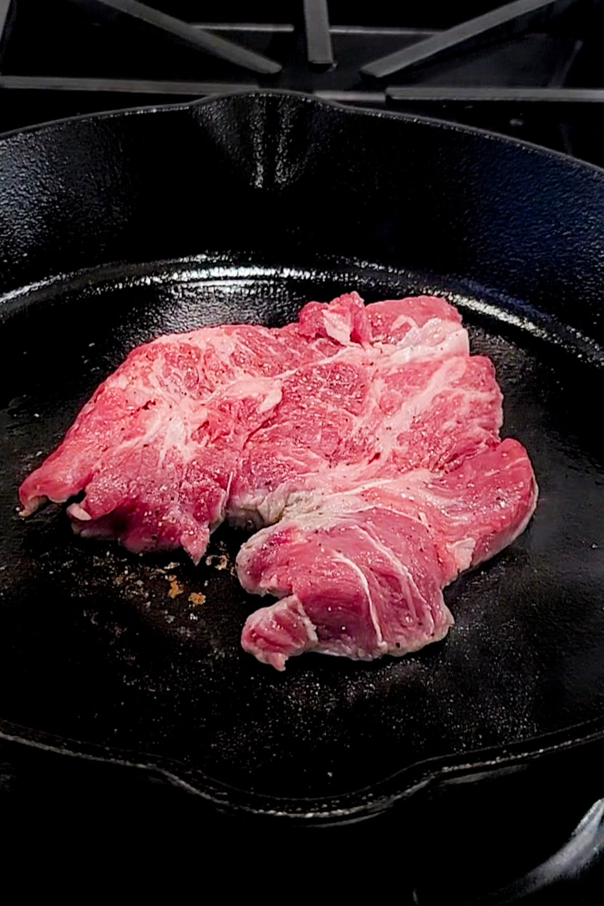 Steak in a pan being seared.