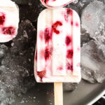 A Raspberry Greek Yogurt Popsicle on a tray filled with ice.