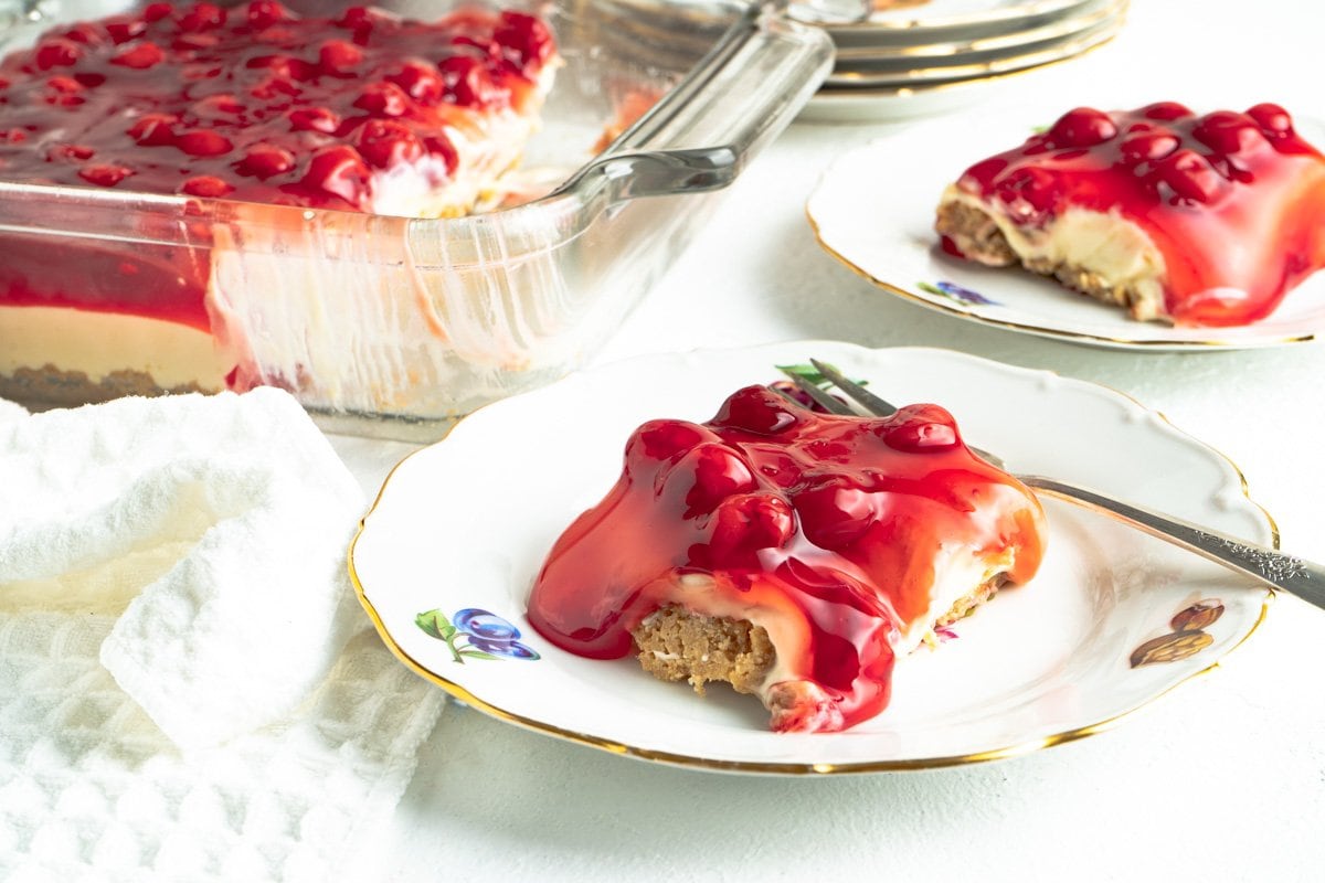 A slice of a cherry cheesecake dessert on a gold rimmed plate.