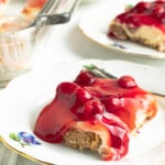 A slice of a Philadelphia no bake cherry cheesecake on a gold rimmed plate with a fork.