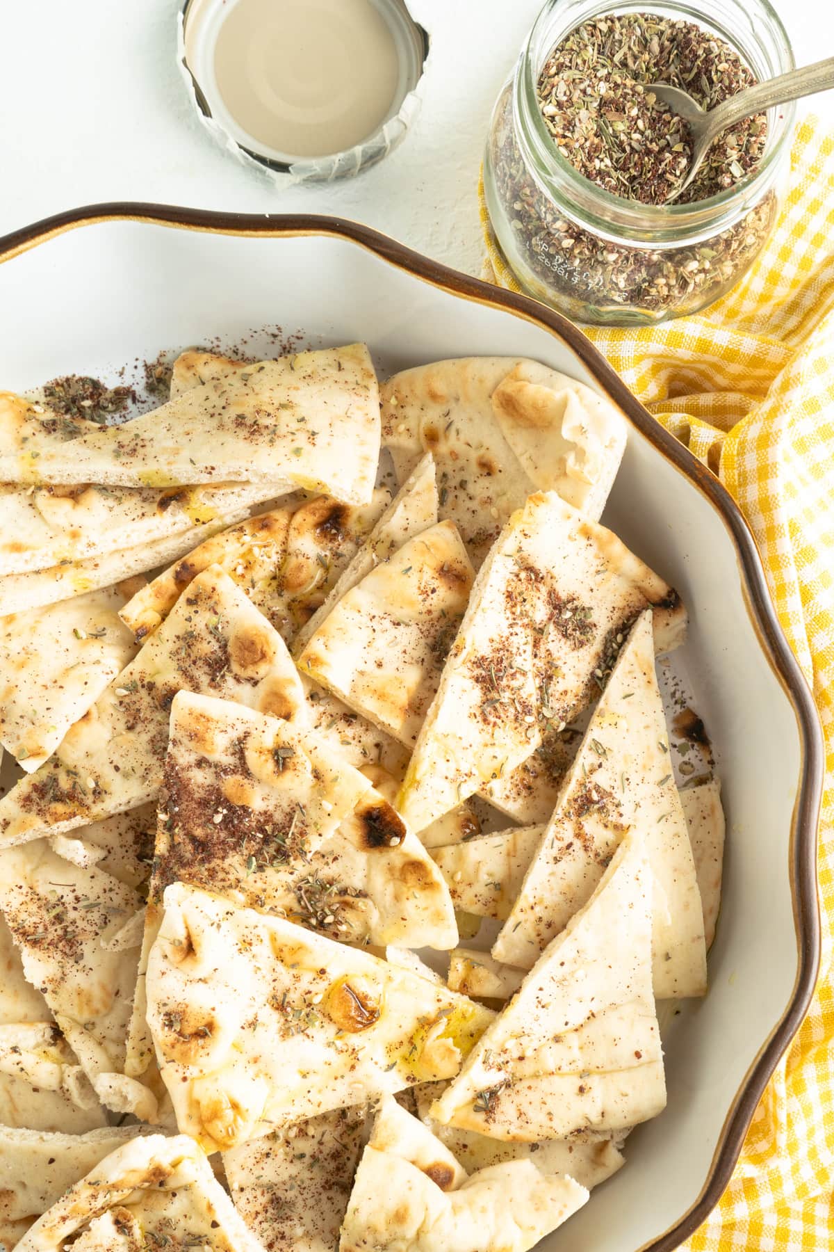 Pita triangles in a bowl covered in zaatar spice mix and olive oil.