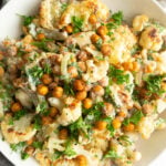 Close of of a cauliflower and chickpea salad in a white bowl.