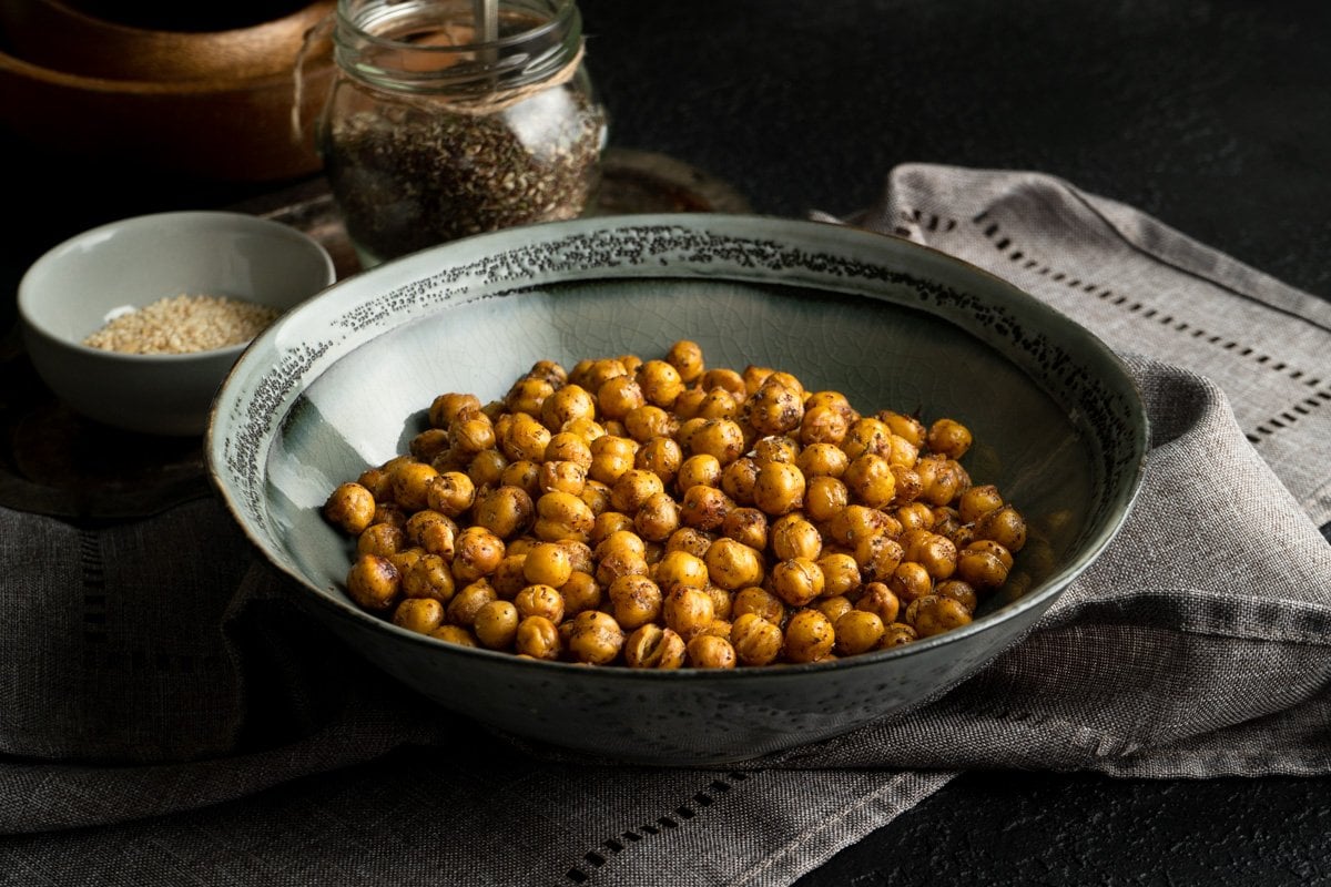 A roasted chickpea recipe in a grey bowl on a dark table.