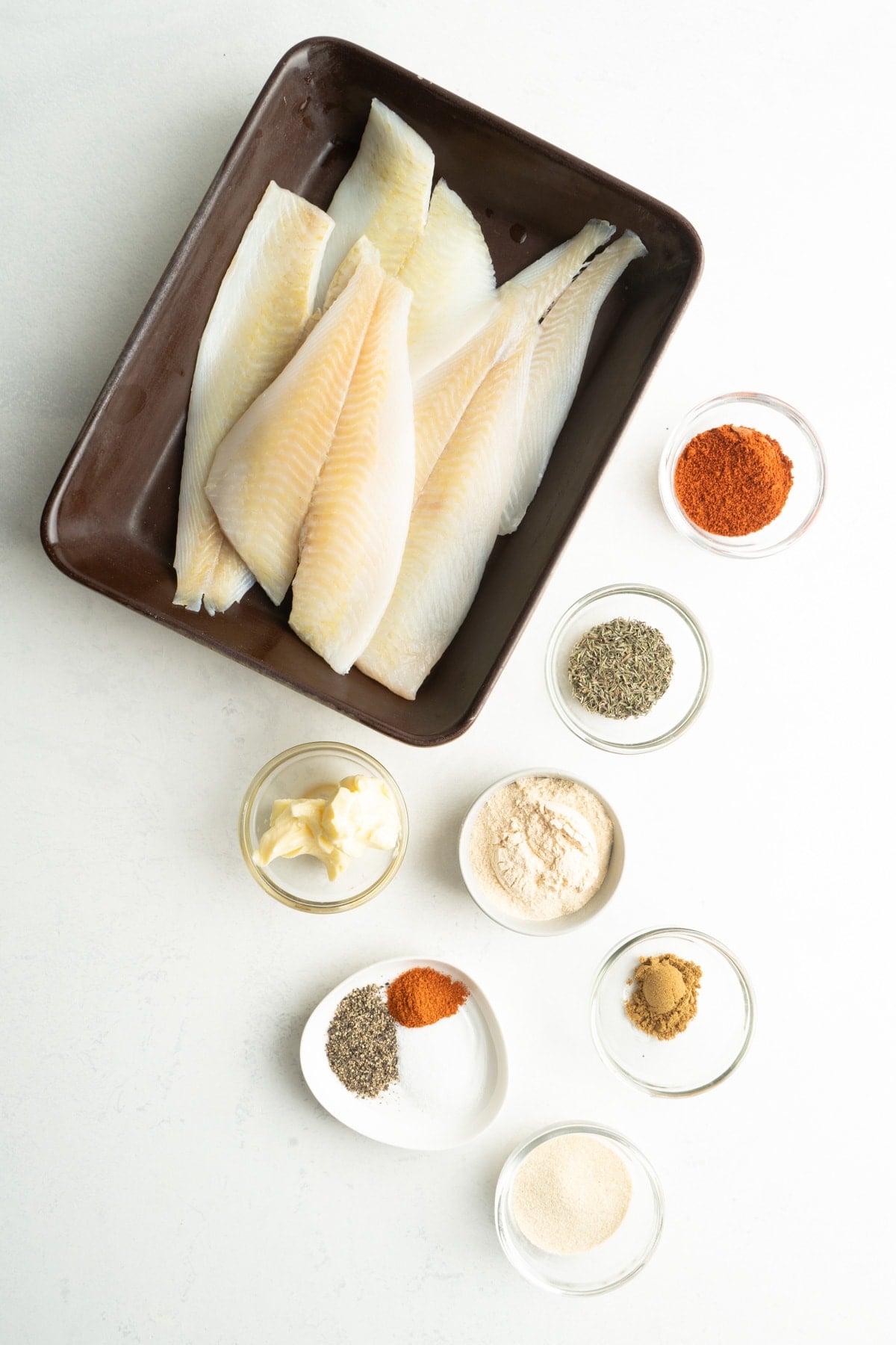 Raw white fish and ingredients for blackened fish seasoning.