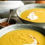 Pinterest pin showing two bowls of lentil soup on a table.