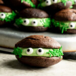 Monster chocolate whoopie pies on a tray with one close up.