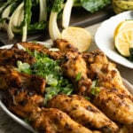 Baked turkey wings on a platter with vegetables around.